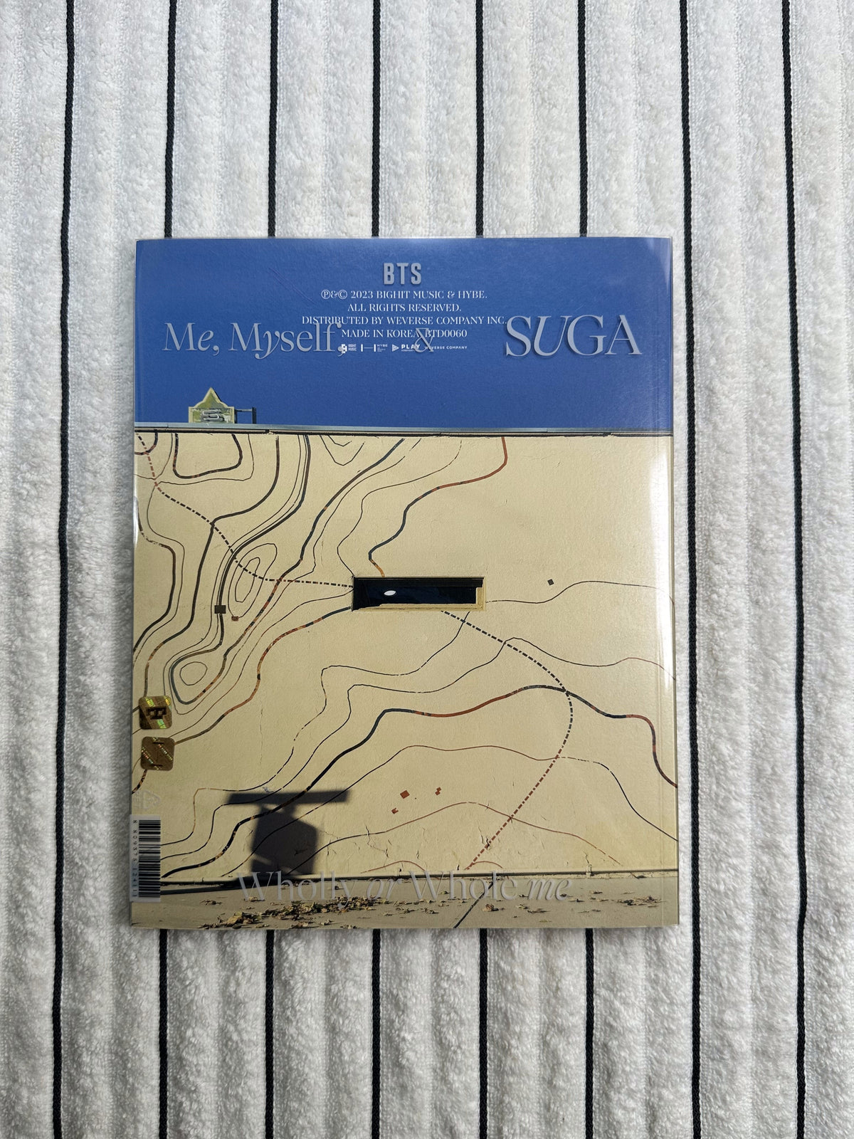 Album cover with topographic design and blue label on a striped background
